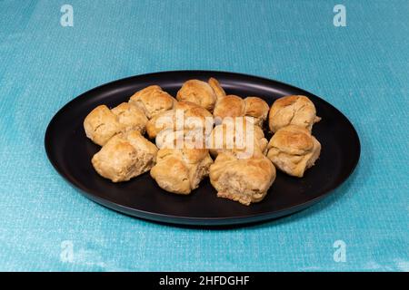 A plate covered in fresh backed, golden brown, home cooked biscuits sitting on a table in preparation for a meal. Stock Photo