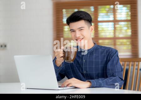 Young business man working from home with laptop computer on desk, freelance male sitting stay home using notebook for communication and relax on tabl Stock Photo