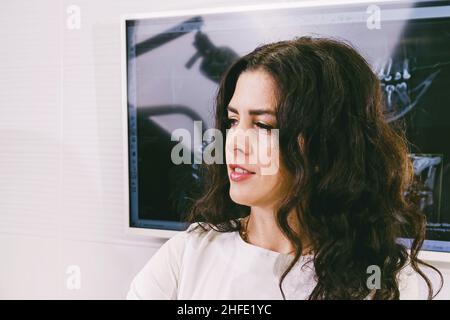 Close up photo of a woman stomatologist looking aside sitting in front of the monitor with teeth snapshot. Stock Photo