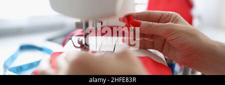 Female hands thread red thread into a sewing machine Stock Photo