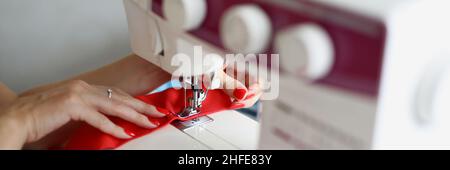 Woman seamstress sews a seam on a sewing machine Stock Photo