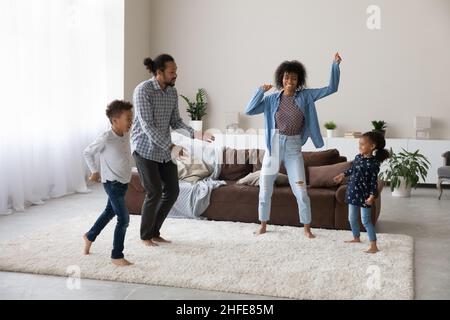 Cheerful excited active African family dancing to music, going wild Stock Photo