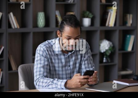 Focused busy millennial Black business man browsing internet on smartphone Stock Photo