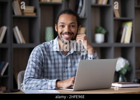 Happy Afro American entrepreneur guy sitting at desk Stock Photo