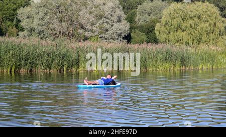 man sleeps on a SUP-board. rest on the water Stock Photo