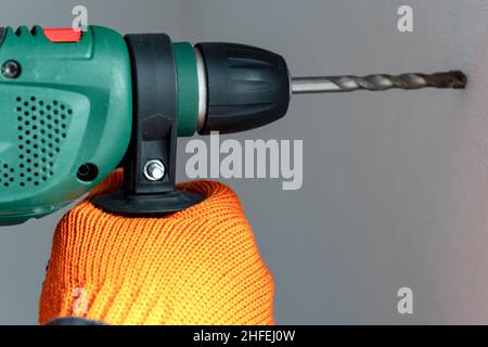 workman with a hammer drill. Hands in protective gloves with hammer drill perforator. close-up Stock Photo