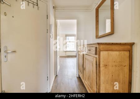 Delightful corridor with a solid wooden chest of drawers in daylight Stock Photo