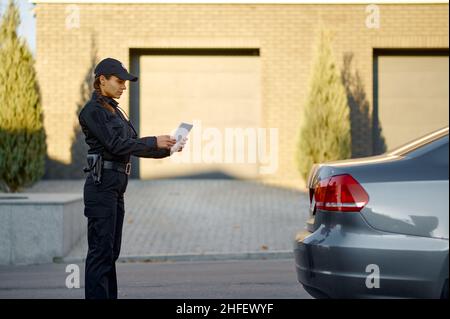 Woman police officer check stopped car number Stock Photo