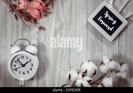Spring Forward text on chalkboard and light gray rustic wood flat lay with alarm clock and natural elements.  Daylight Saving Time concept. Stock Photo