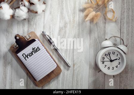 PRIORITIES text on notepad rustic wood flat lay with alarm clock and natural elements.  Time management concept. Stock Photo