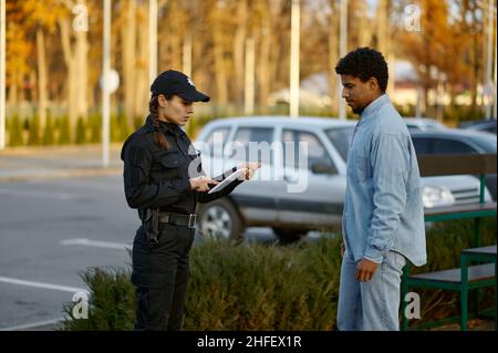 Female cop checking male passerby ID document Stock Photo