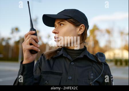 Portrait of female cop communicating on walkie-talkie Stock Photo