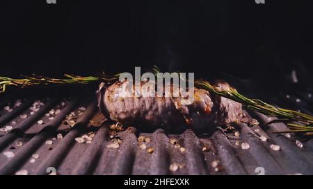 Delicious juicy meat steak cooking on grill. Aged prime rare roast grilling tenderloin fresh marble tenderness beef. Prime beef fry on electric roaster, rosemary, black pepper, salt. Slow motion. Stock Photo