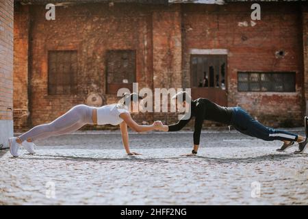 Handsome young couple doing one arm pushup exercise in the urban environment Stock Photo