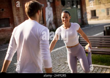 Sporty young woman doing stretching exercise after jogging with her personal trainer Stock Photo