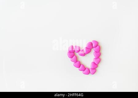Valentine's day pattern background flat lay top view of heart shaped pink candies scattered on white background. Place for an inscription