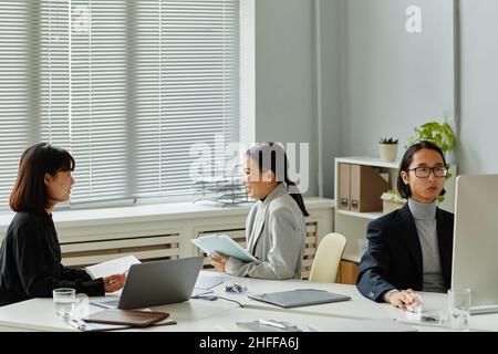 Modern team of Asian business people working on project together in office, copy space Stock Photo