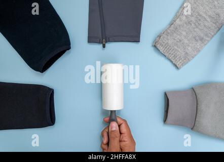 Close up photo of sticky lint roller or hair remover and clothes produced of different kinds of materails. Stock Photo