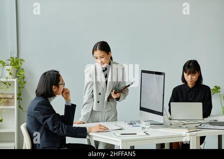 Portrait of smiling Asian businesswoman working with team of colleagues in modern office, copy space Stock Photo