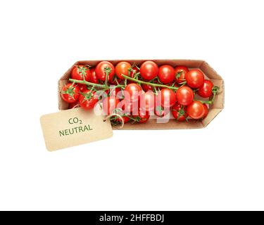 Isolated organic cherry tomatoes in an eco friendly craft package with a label with the inscription carbon neutral on a white background. Season locka Stock Photo