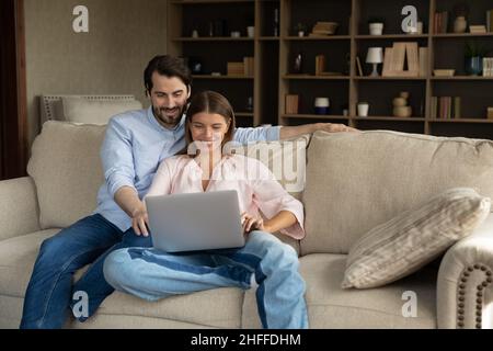 Married couple sit on cozy sofa with laptop Stock Photo