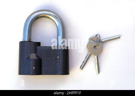 Gray padlock with keys. A padlock with a thick handle and three steel keys. Large padlock on a white background top view. Stock Photo