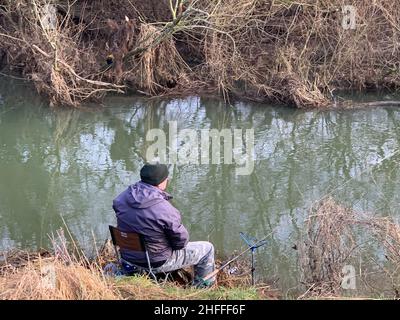 Man fishing at Wolverton near Cosgrove Milton Keynes UK river fishing rod catch weather winter calm great Ouse fishery Buchinghamshire Stock Photo