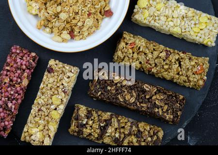 Oatmeal bars with berries and cornflakes. Healthy nutritious snacks. fitness bars on black background top view. Delicious and healthy food. Granola ba Stock Photo