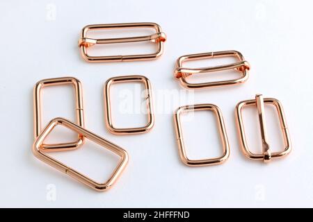 Belt adjuster frames, color red gold. Metal frame with a movable part for changing the length of the strap on the bag. Accessories for sewing backpack Stock Photo