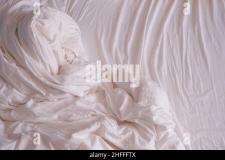 Beautiful white shiny crumpled fabric sheets on the bed. Stock Photo