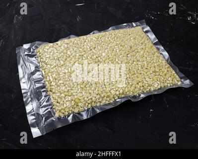 Vacuum packed pine nuts without shells on a black background. Pine nuts in a package close up. Nuts in vacuum packing. Stock Photo