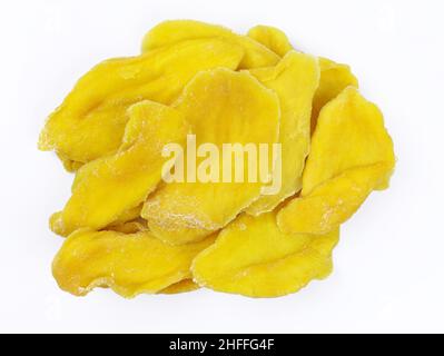 Dried pieces of mango on a white background. Sugar-free sliced dried mango top view. Delicious and healthy dried fruits. Stock Photo