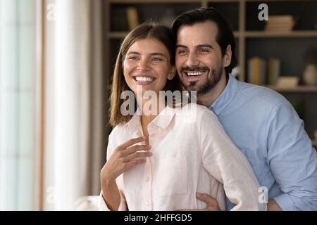 Beautiful couple standing in living room smiling looking into distance Stock Photo