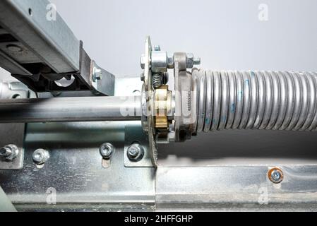 Springs tensioning the garage door mechanism, visible spring with a blue color and a spring protection. Stock Photo
