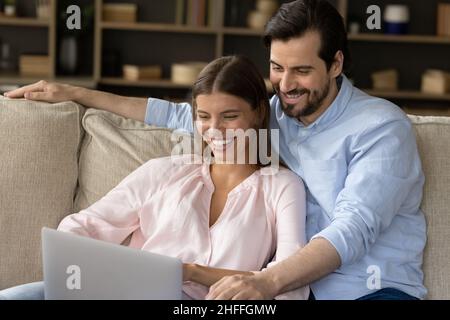 Beautiful couple relaxing on couch in living room with laptop Stock Photo