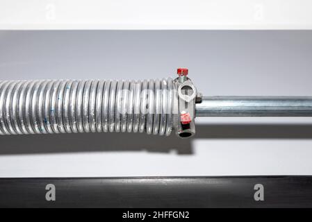 Springs tensioning the garage door mechanism, visible blue spring and spring head. Stock Photo