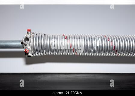 Springs tensioning the garage door mechanism, visible red spring and spring head. Stock Photo