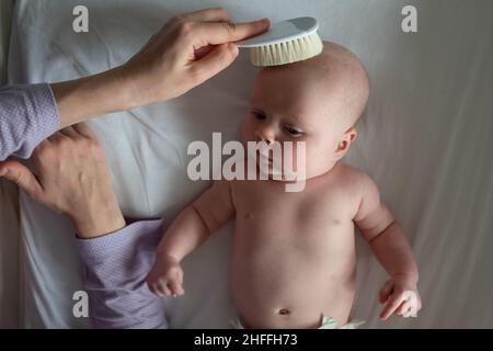 Caucasian mother combing hair newborn girl. Motherhood concept Stock Photo