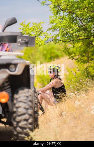Beautiful girl is sitting on the grass while taking a break Stock Photo
