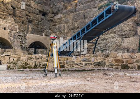 archaeological site among antique ruins with a conveyor for stones and a theodolite in the foreground Stock Photo