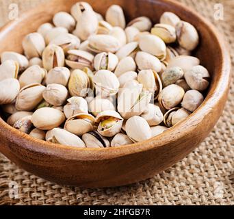 Pistachio nuts in shell  in bowl on wooden background. Stock Photo