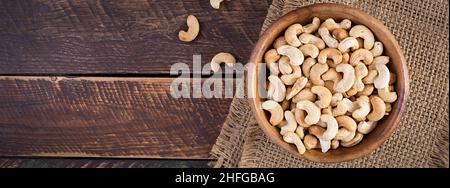 Tasty cashew nuts in bowl on wooden table. Top view, banner Stock Photo