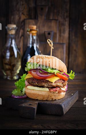 Hamburger with bacon, turkey burger meat, cheese, tomato and lettuce on wooden background. Tasty burger. Close up Stock Photo