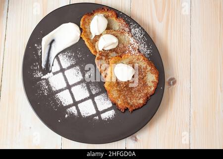 Potato fritters, draniki, deruny, potato latkes, latkas, irish cakes, raggmunk, tocinei or boxties, hash browns. Vegetable pancakes on a black plate Stock Photo