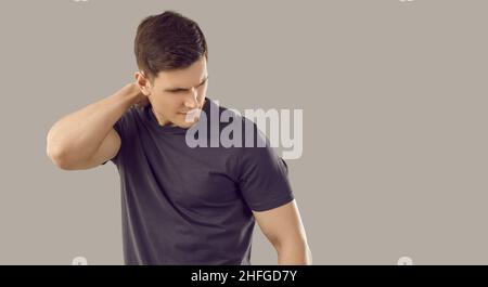 Young unhappy muscular man suffers from neckache due to muscle spasm or pinched nerve. Stock Photo