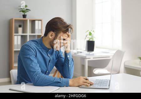 Stressed, exhausted and frustrated young employee has a burnout at work in office Stock Photo