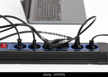 Close up of a plug in an electrical socket on a table at home with many connections and electrical overload Stock Photo