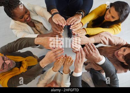 Top view of diverse team of happy business people joining their hands and smiling Stock Photo