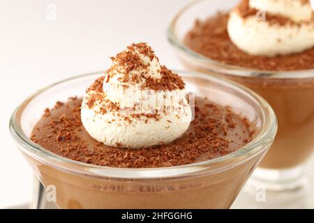 Chocolate mousse dessert in a conical glass dish topped with a swirl of cream and grated dark chocolate sprinkled over the top Stock Photo