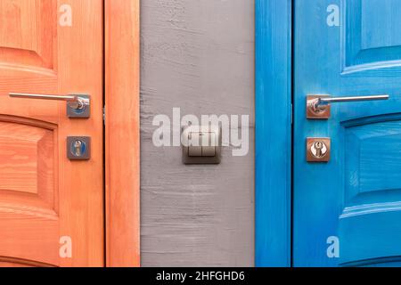 Orange and blue wooden door with iron handle and light switch next to part or element of the interior in the toilet.